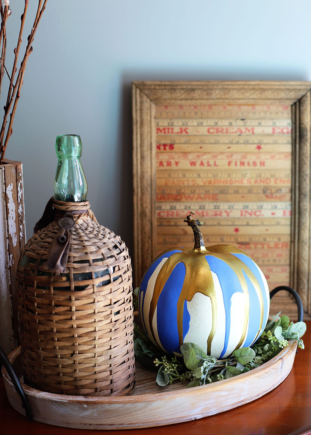Paint dripped pumpkin setting on a tray with French farmhouse decor.