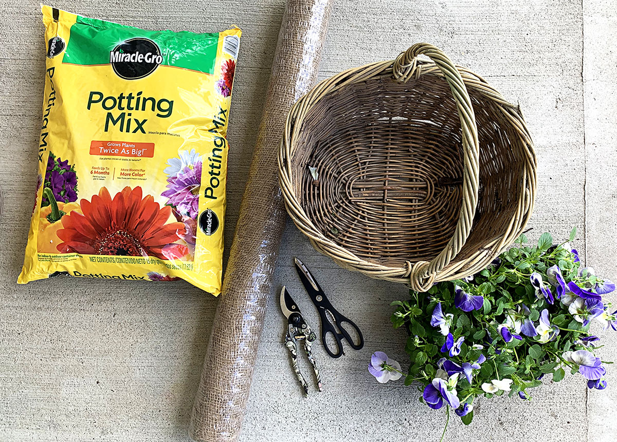 potting soil, roll of burlap, scissors, pansies, basket and pruning shears.