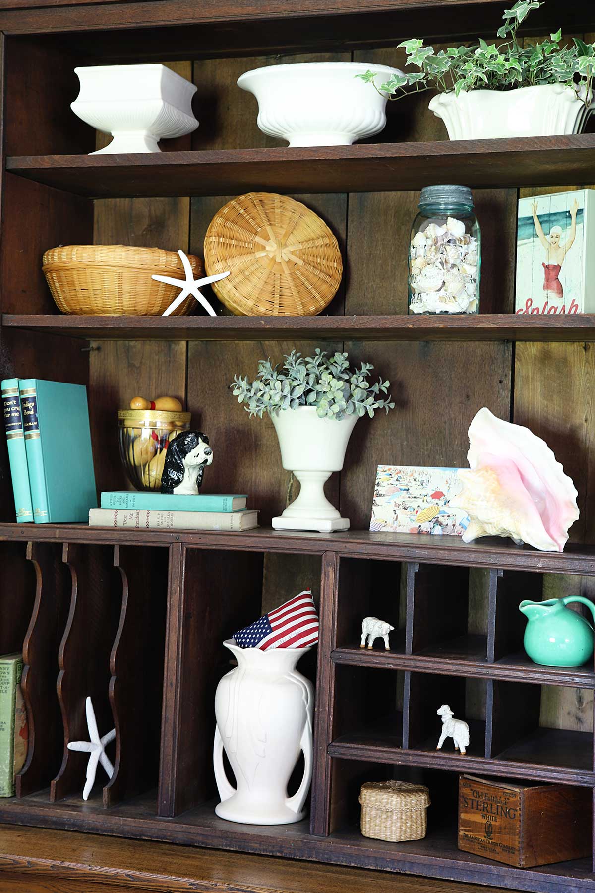bookcase shelves decorated for summer with shells and beach theme