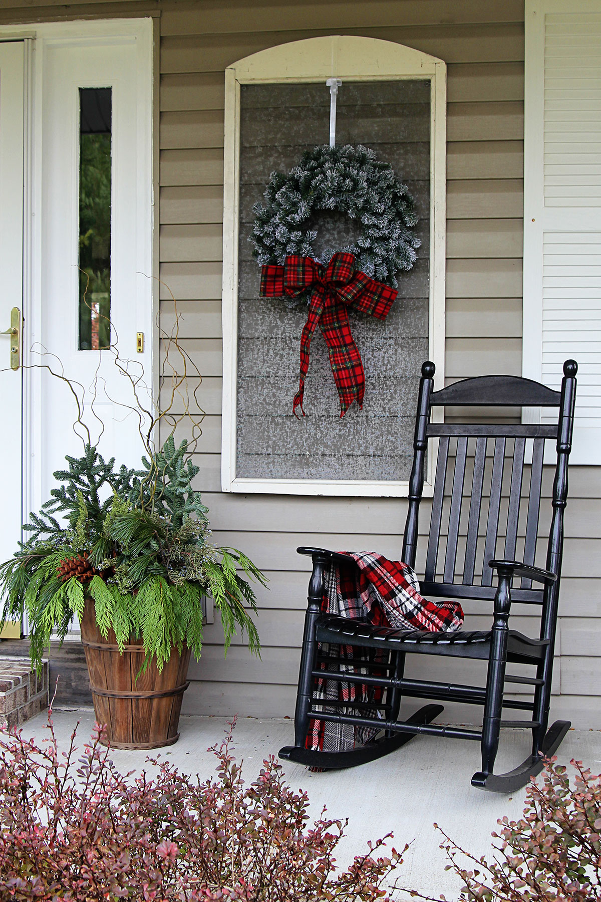 Cozy porch decor showing a black porch rocker with a plaid throw over the arm for winter porch decor.