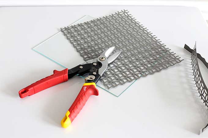 Using tin snips to cut aluminum sheet for craft project