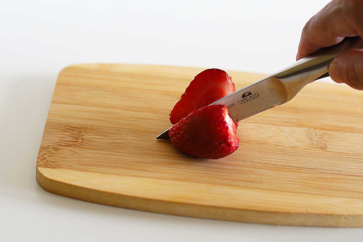 Cutting strawberries in half.