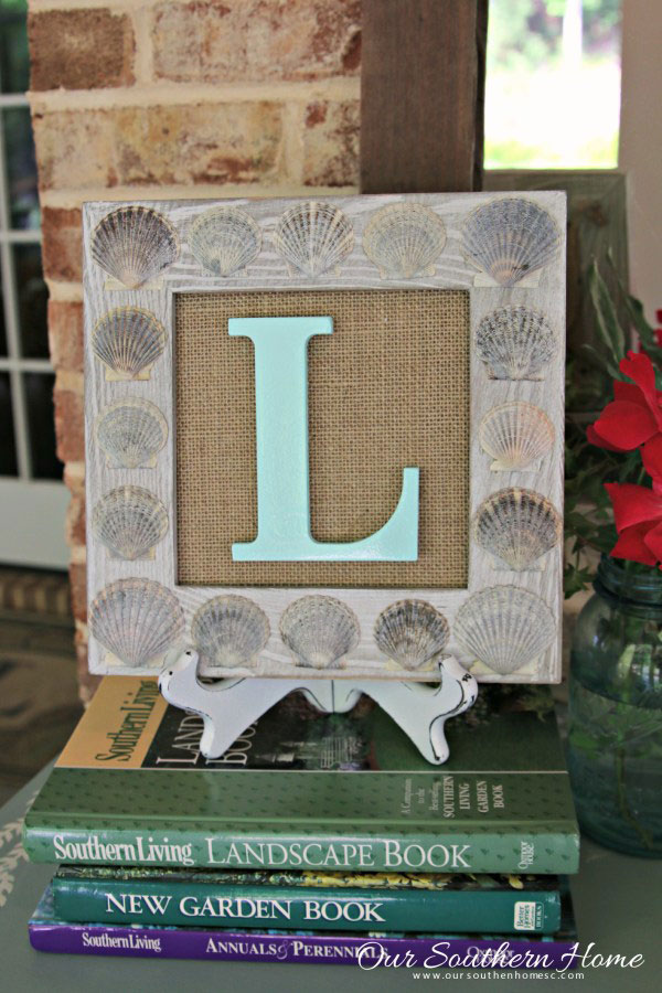 Wooden frame covered in sea shells with a monogram letter L.