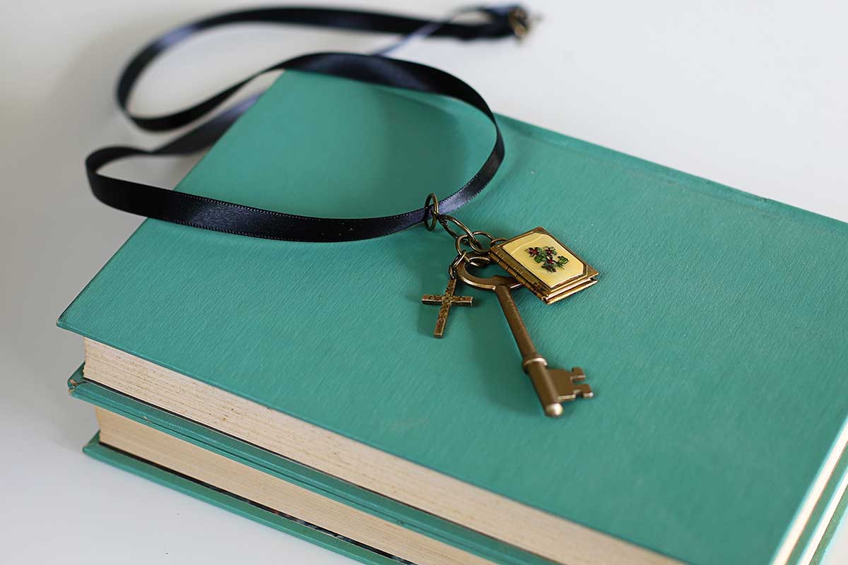 Skeleton key necklace sitting on top of aqua books. 