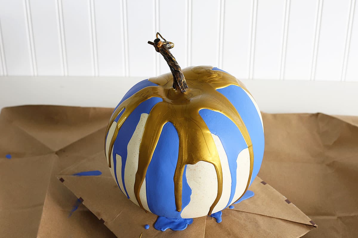 Pumpkin with gold and blue paint splatters on it.