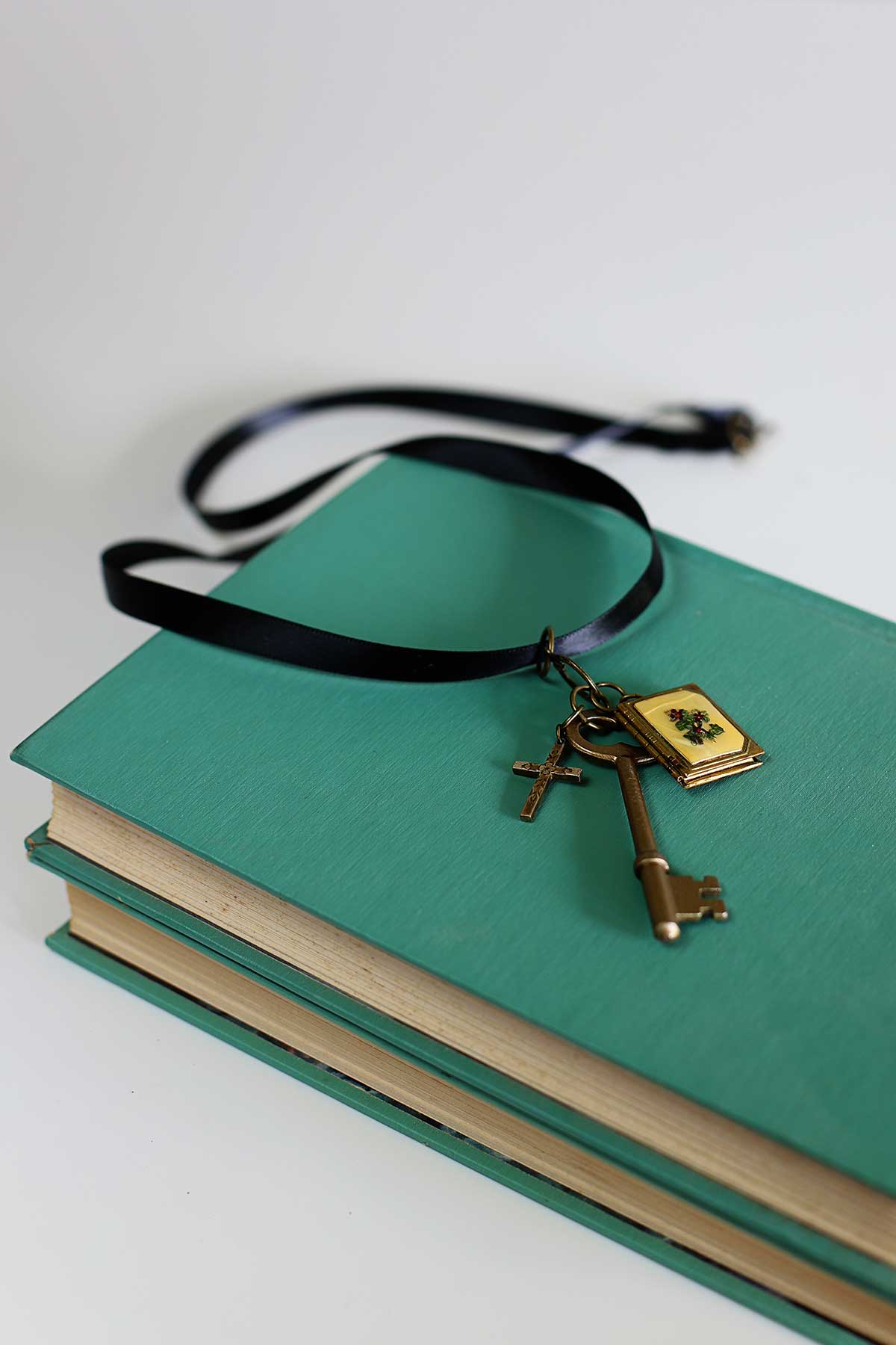 DIY vintage skeleton key necklace sitting on a stack of aqua books.