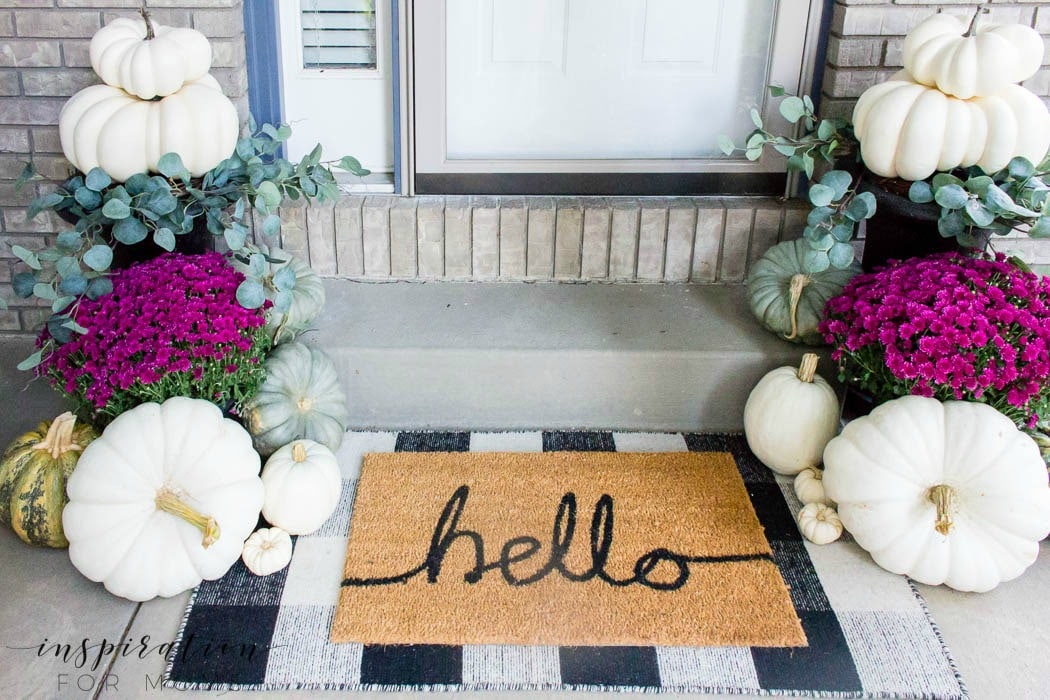 Layering a doormat that says hello onto a larger black and white buffalo check doormat.