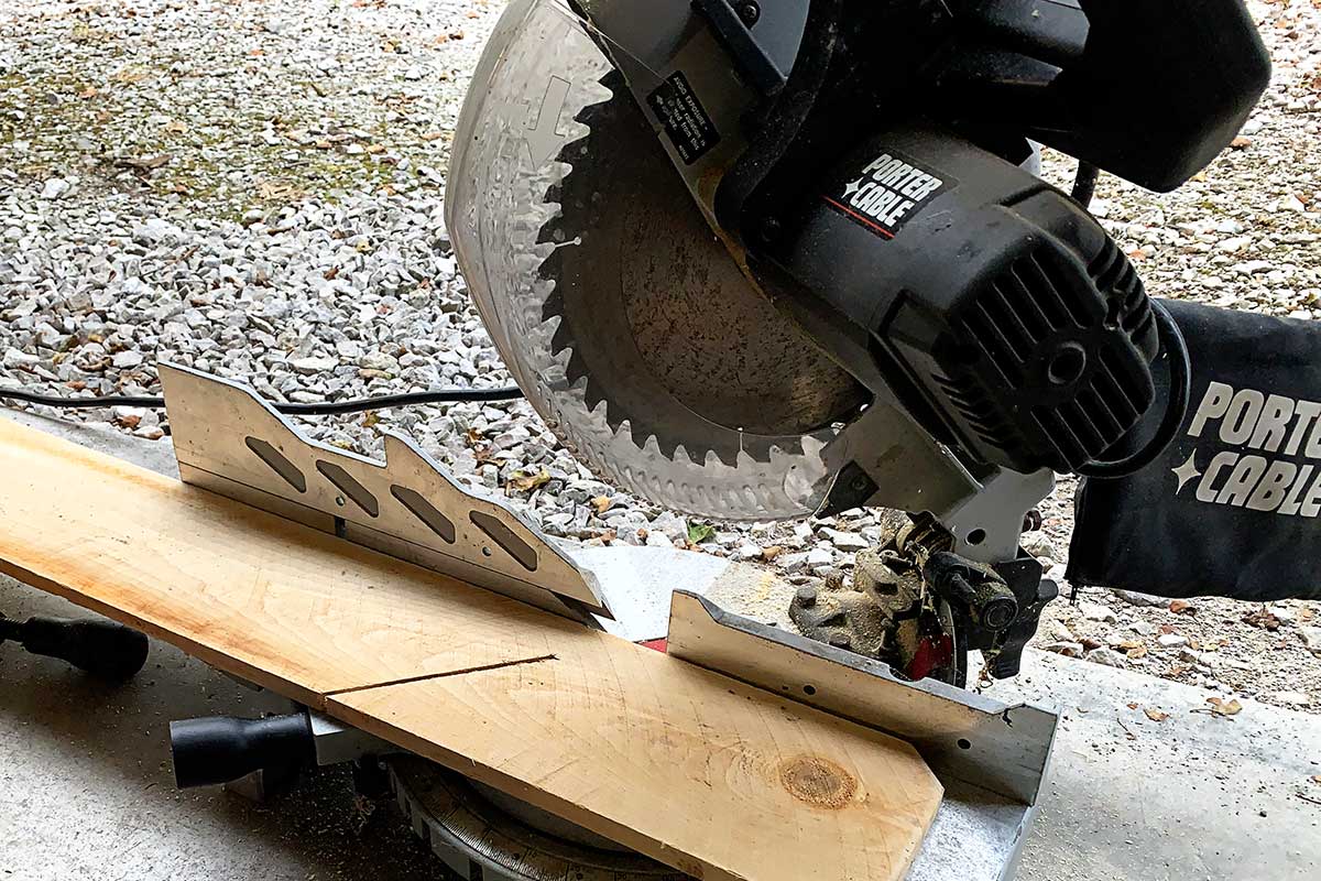 Using a miter saw to cut cedar fencing pickets to make angel wings.