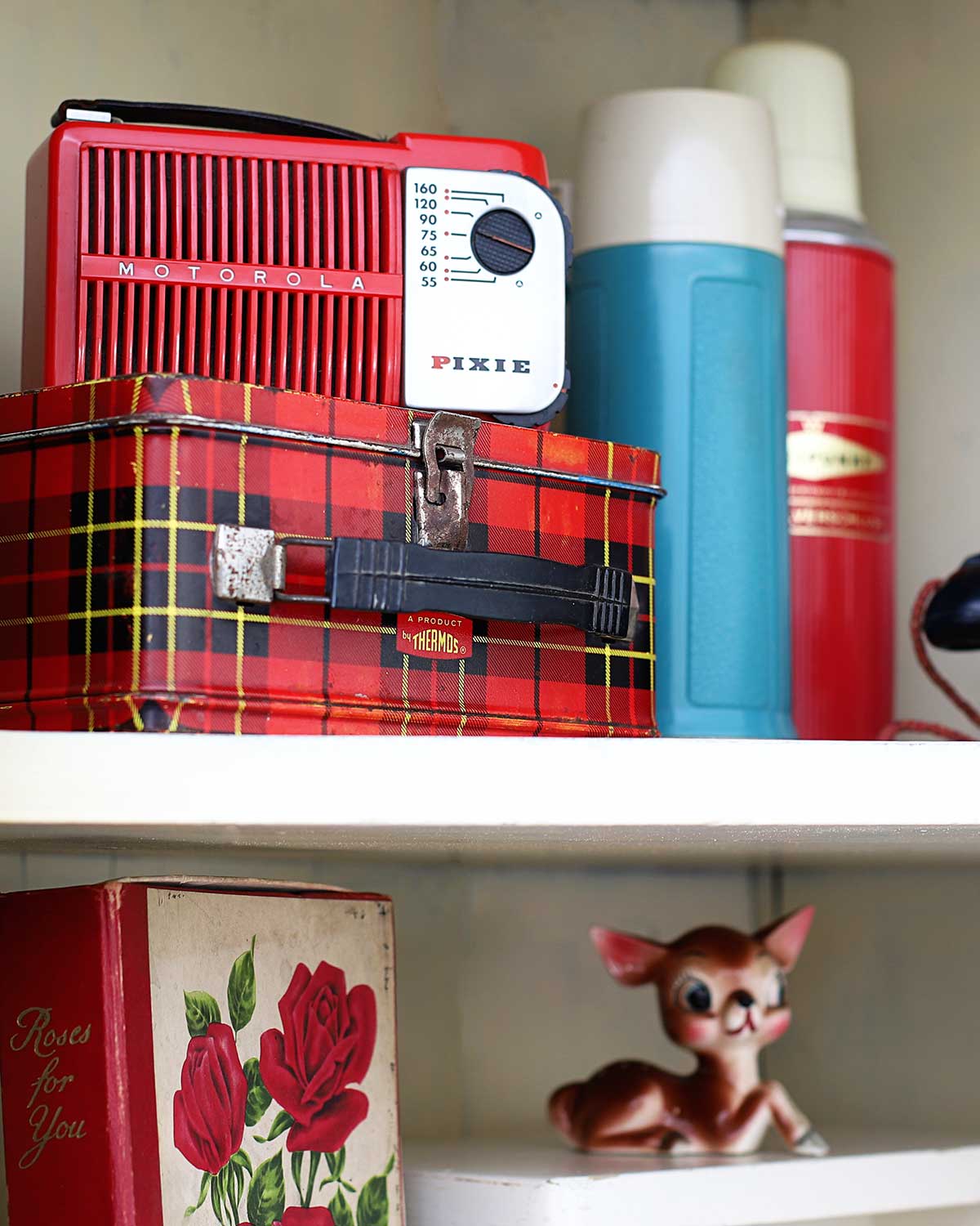 A red Motorola Pixie radio, vintage plaid school Thermos lunchbox and thermoses