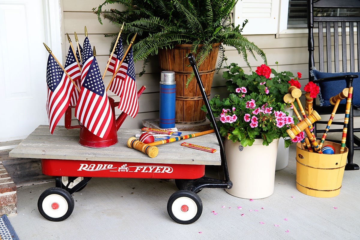Radio Flyer wagon with a red watering can with flags in it.