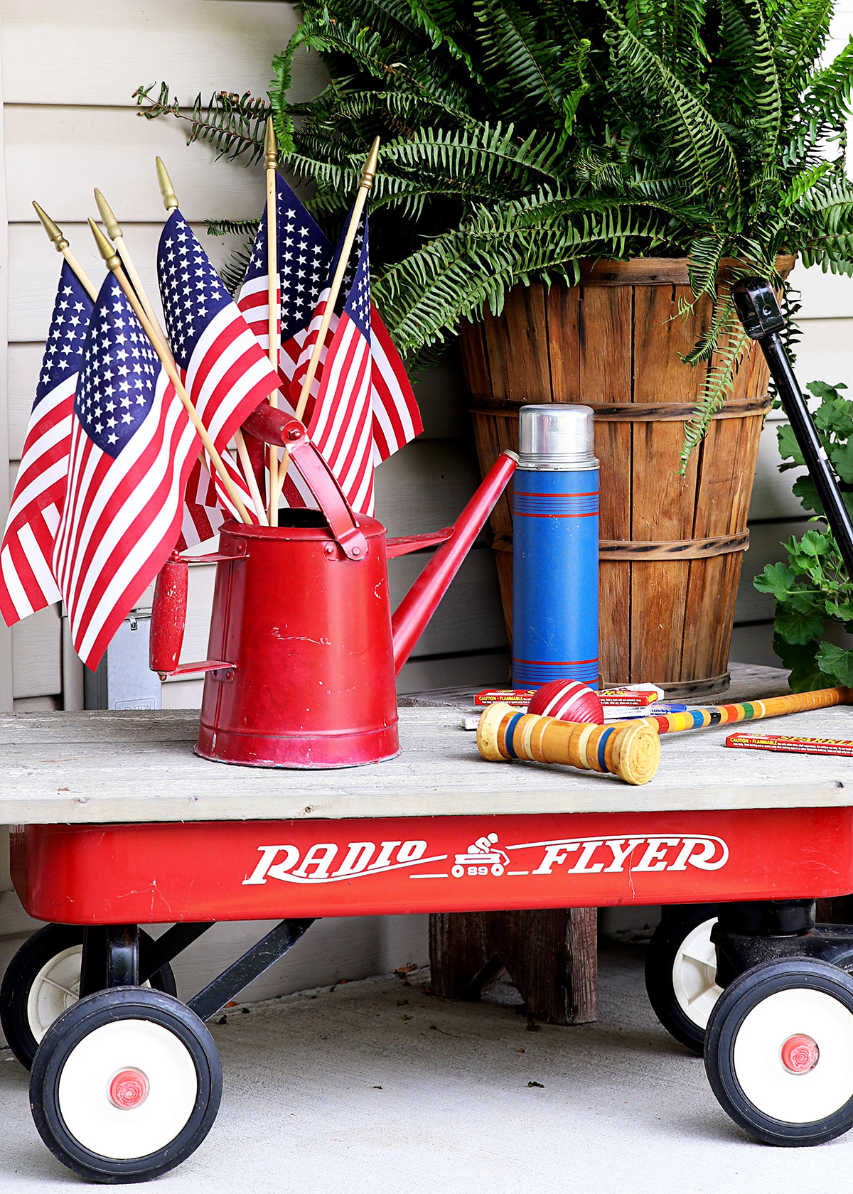 Red Radio Flyer wagon sitting on porch for Fourth Of July decorations. 