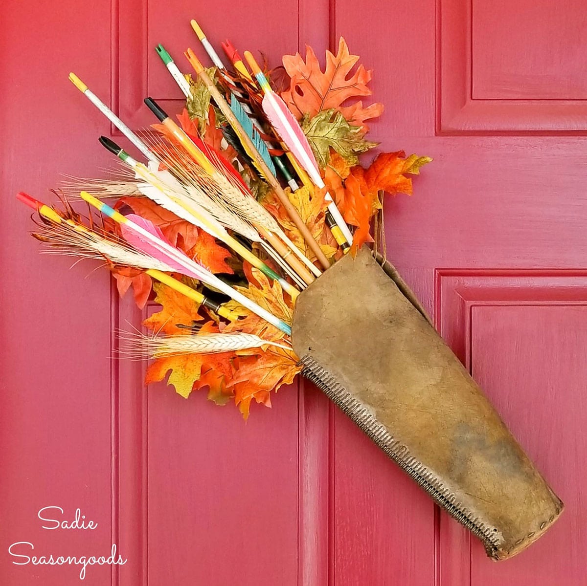 quiver of arrows hung on red door as fall wreath