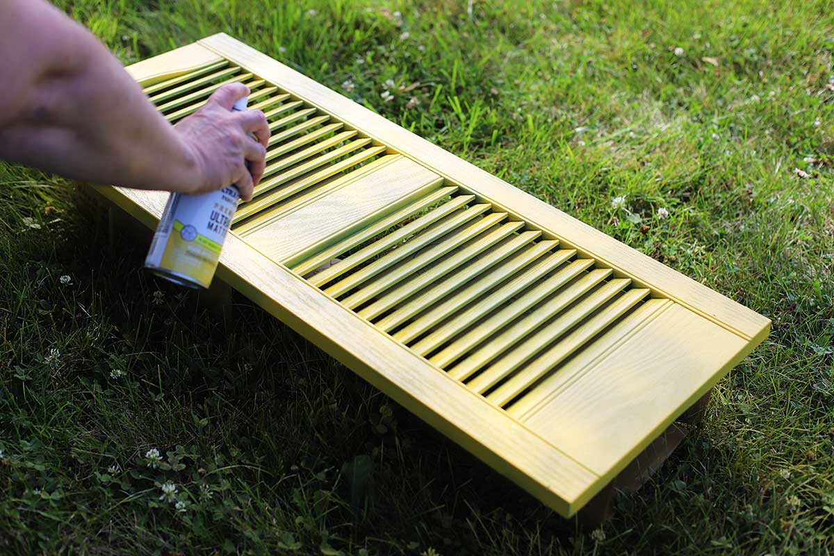 Spray painting a shutter yellow.
