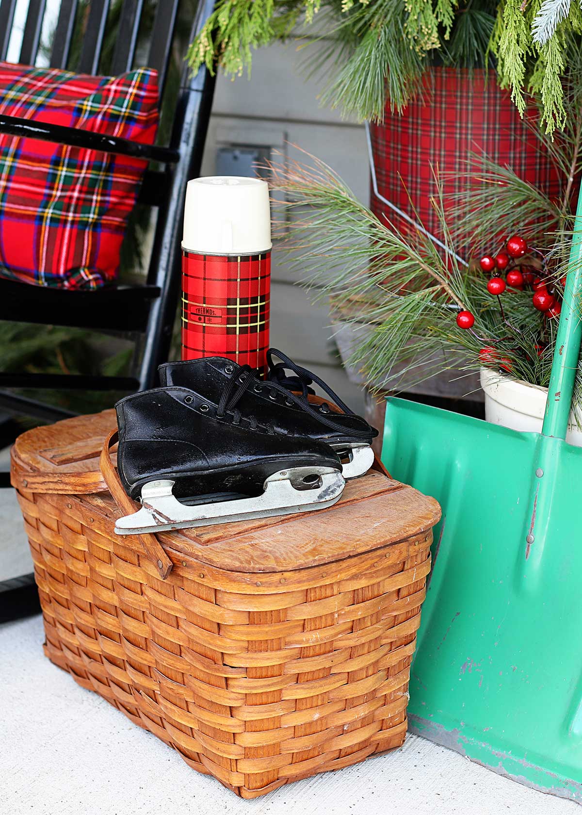 vintage picnic basket with ice skates and thermos on Christmas porch