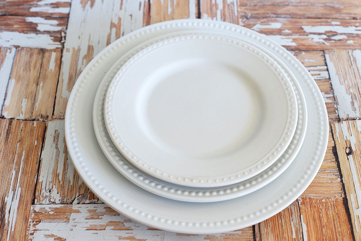 3 white plates setting on a rustic white wood background. 