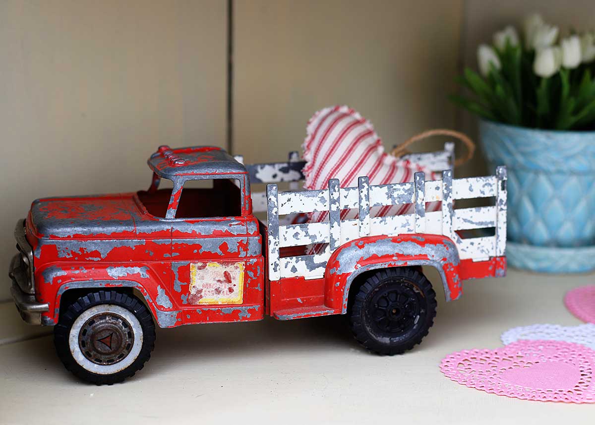 vintage red toy pickup truck with Valentines Day heart in the back