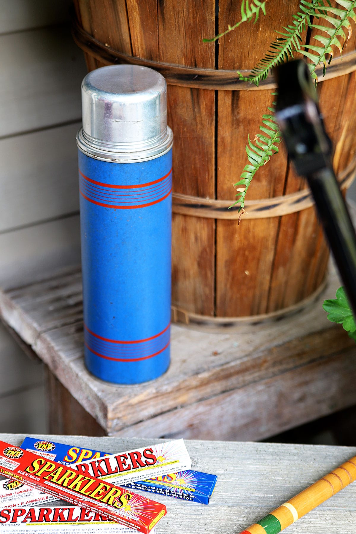 Blue vintage thermos sitting on bench as part of 4th Of July decorations. 