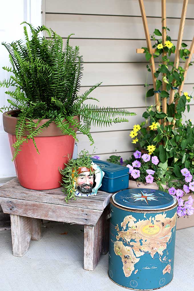Boho styled summer porch decor using thrift store mug as a planter and vintage cooler as decor