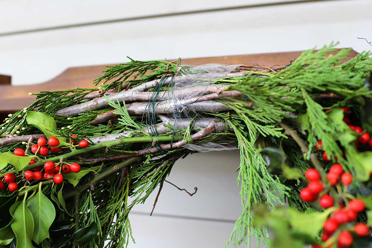 using packing tape to keep evergreens in place on wreath